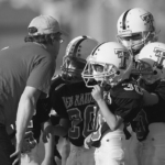 coach talking to four young football players