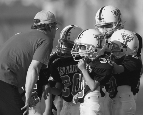 coach talking to four young football players