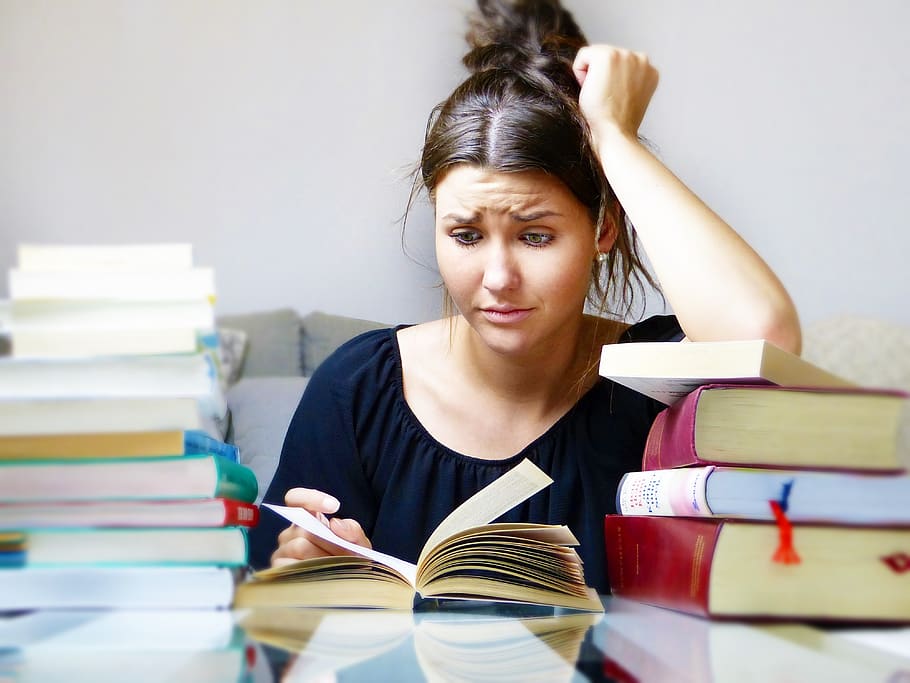 College student busy with stacks of books