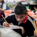 Young boy working on class work with other students