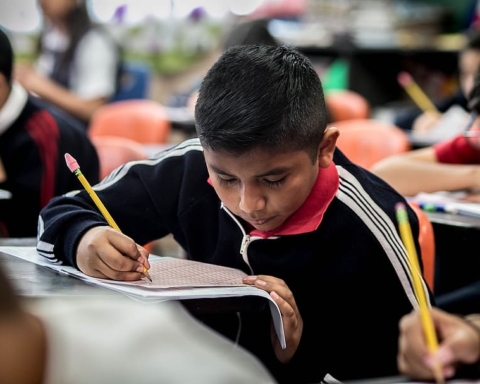 Young boy working on class work with other students