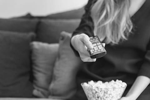 person holding bowl of popcorn and television remote